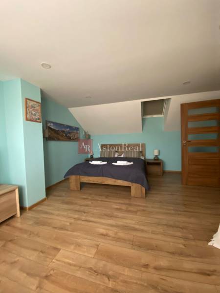 Family house: Sloped ceiling, double bed, wooden floor, blue wall, and nightstands.