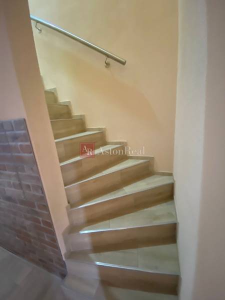 A staircase in a family house with a brick wall and a steel railing.