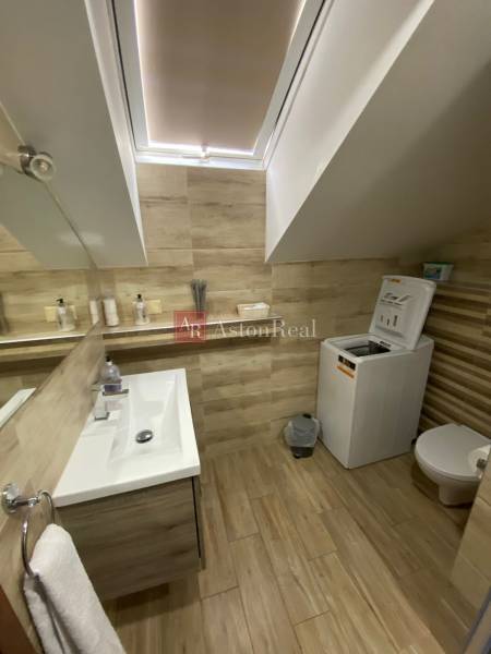 A bathroom in a family house with a sink, washing machine, and toilet in light wooden tones.