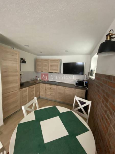 A kitchen in a family house with wooden furniture, a dining table, and a brick wall.