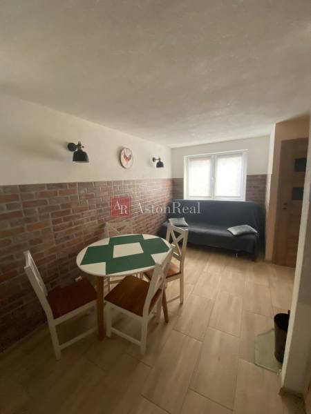 A room with a brick wall, a table, chairs, and a sofa in a family house.