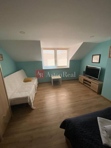 A room in a family house with a sofa, television, and wooden floor.