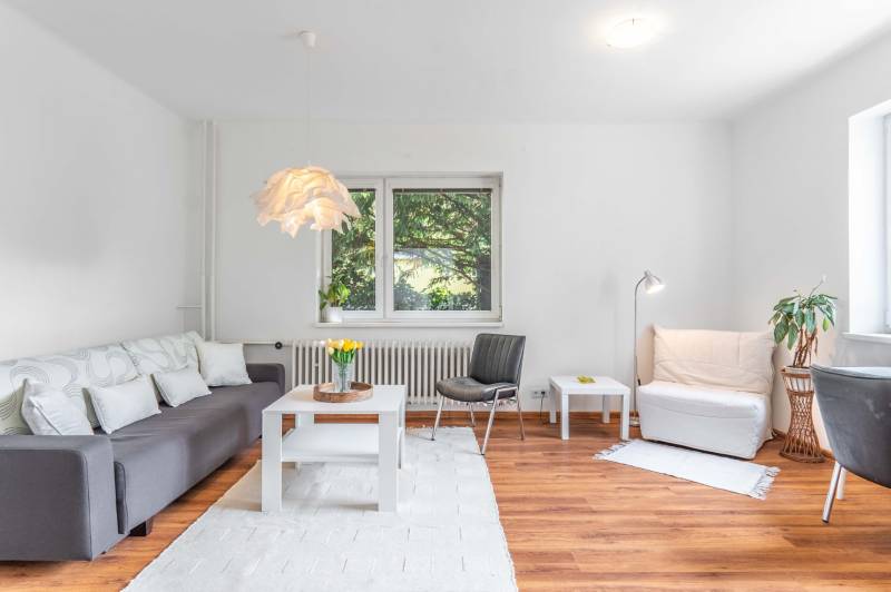 Living room of a two-room apartment with a sofa and wooden floor, light decoration.