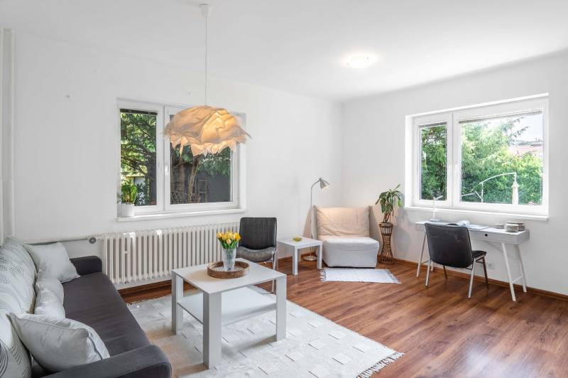 Bright living space in a 2-room apartment with a sofa, table, and desk.