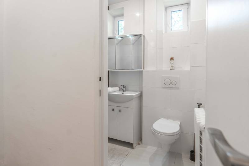 Bathroom with a toilet, sink, and mirror in a 2-room apartment.