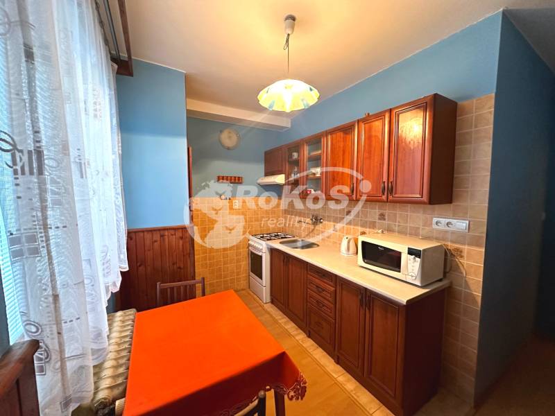 A kitchen in a 3-room apartment with wooden cabinets and a dining table.