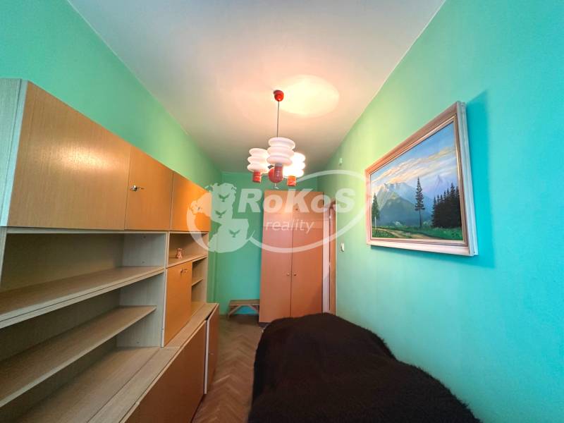 A narrow room in a 3-room apartment with light furniture and a painting on the wall.