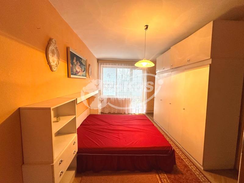 Bedroom with built-in wardrobes, bed with a red blanket in a 3-room apartment.