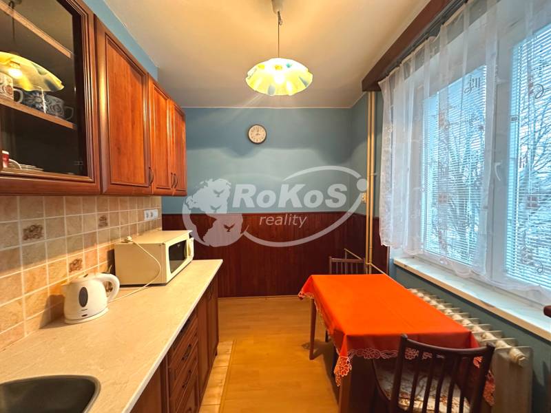 A kitchen in a 3-room apartment with wooden furniture and a dining table.