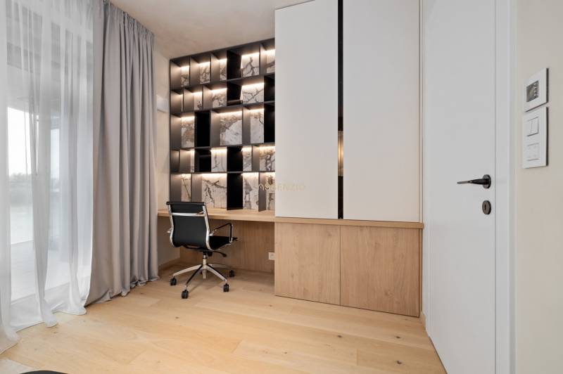 A workspace in a 3-room apartment with wooden flooring and designer lighting.
