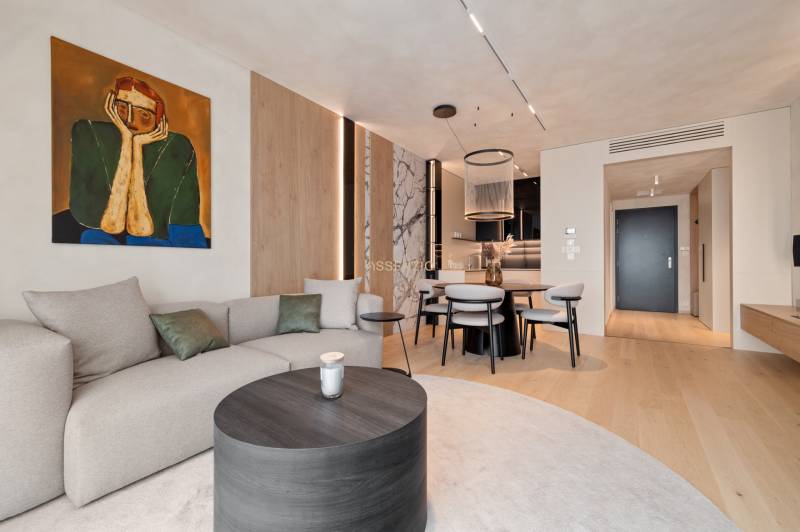 Stylish living space with a sofa, painting, dining table, and wooden floor.