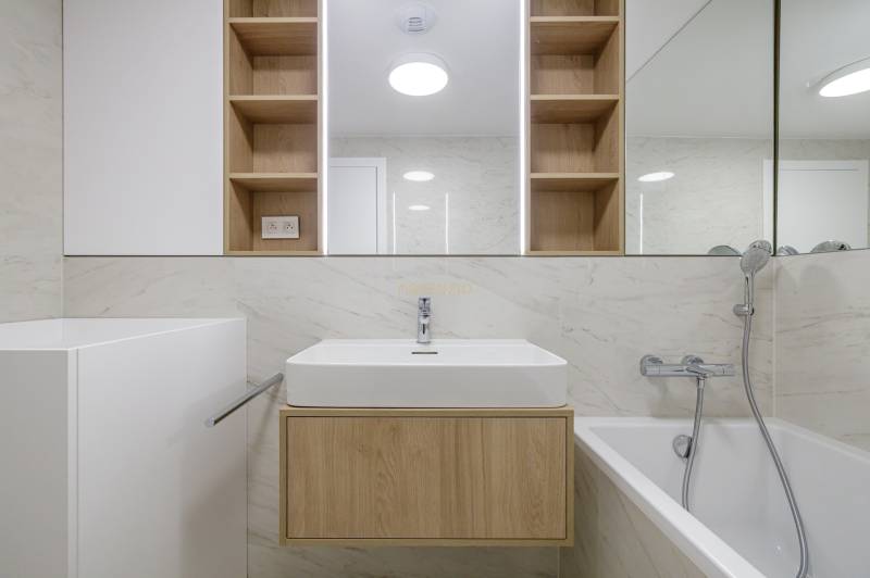 A bathroom in a 3-room apartment with a bathtub, sink, and wooden details.