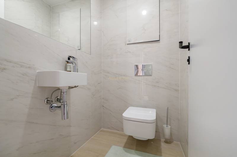 Bathroom with wall-mounted toilet, sink, and tiles in a 3-room apartment.