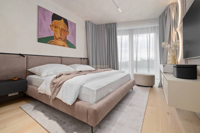 Bedroom in a 3-room apartment with a painting, a large bed, and a TV.