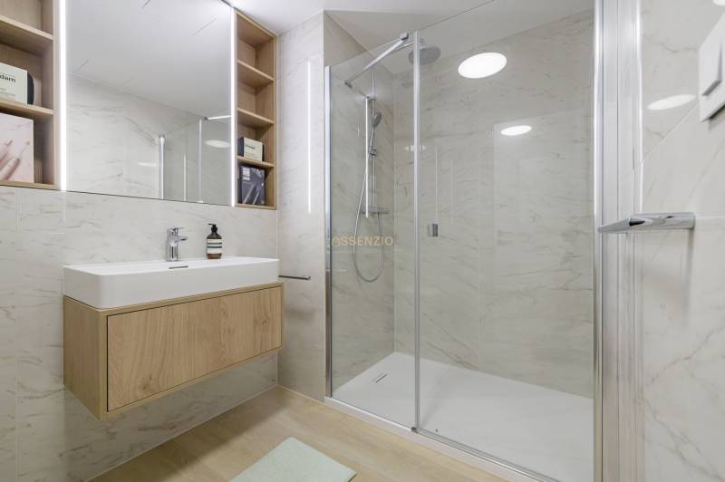 A bathroom with a double mirror, a shower cabin, and a wooden washbasin counter in a 3-room apartment.