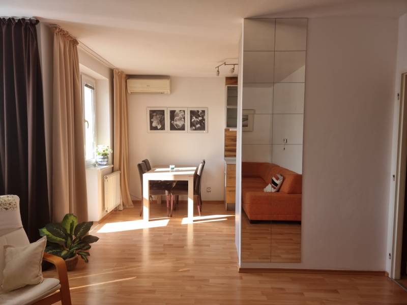Living room in a 4-room apartment with a dining table and an orange sofa.