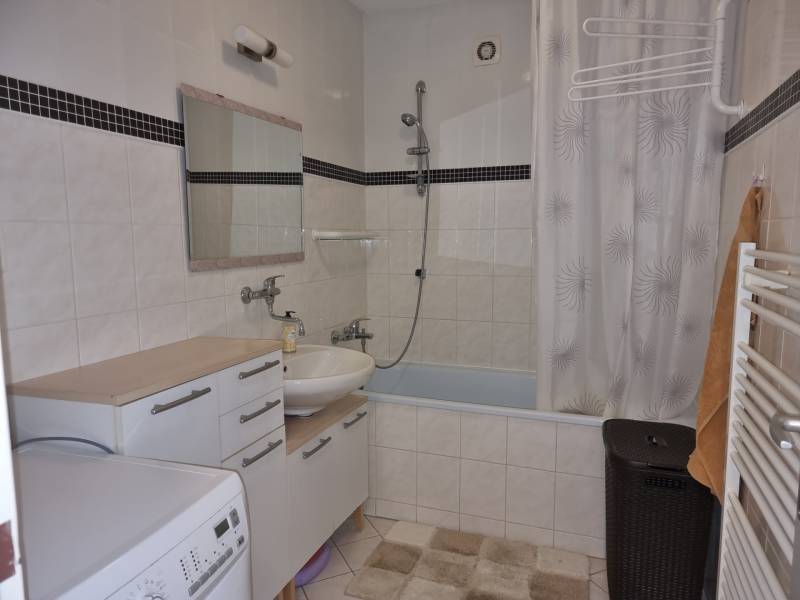 A bathroom in a 4-room apartment with a bathtub, sink, washing machine, and storage cabinets.