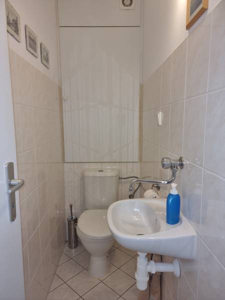 A small bathroom in a 4-room apartment with a toilet, sink, and light-colored tiles.