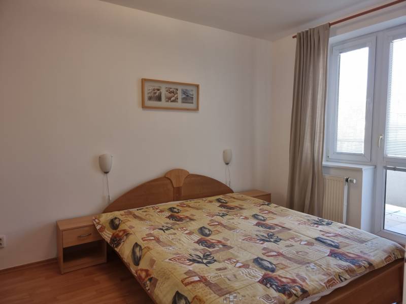 Bedroom in a 4-room apartment with a double bed, a painting, and balcony doors.