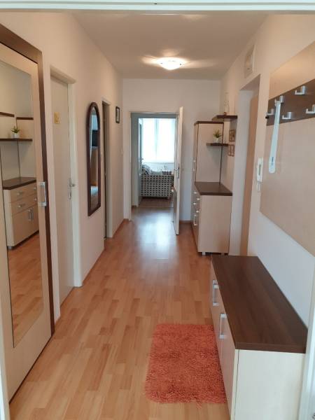 Hallway of a 4-room apartment with wooden flooring, a mirror, and wall cabinets.