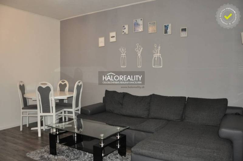 Living room with a gray sofa and a dining table in a 3-room apartment.
