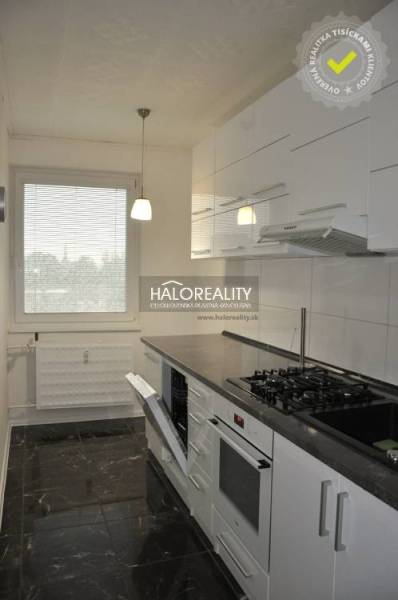 The kitchen in the 3-room apartment has white cabinets and a dark countertop.