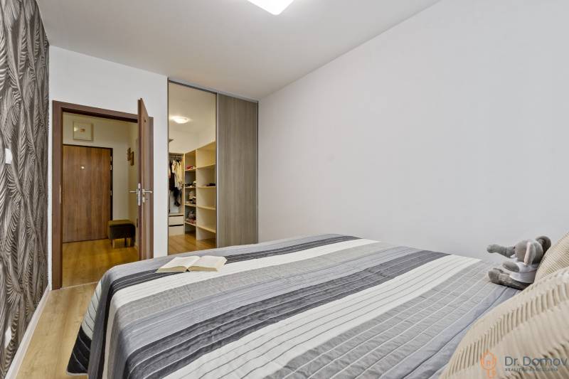 A bedroom with a bed, a book, a plush toy, and a built-in wardrobe in a 2-room apartment.
