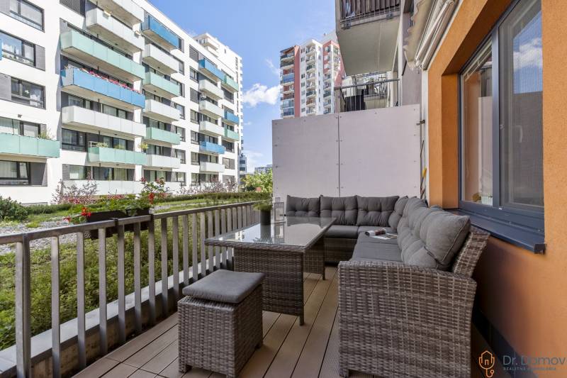 A balcony with seating in a 2-room apartment with a view of Bratislava's apartment buildings in Ružinov.