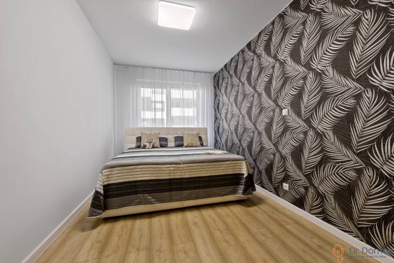 A bedroom with a bed and patterned wallpaper in a 2-room apartment.