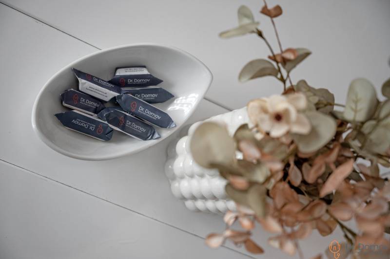 A bowl of candies Dr. Domov next to a vase with flowers on the table in a 2-room apartment.