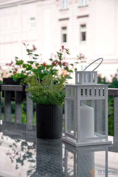 A white lantern with a flower pot on a table in a 2-room apartment.