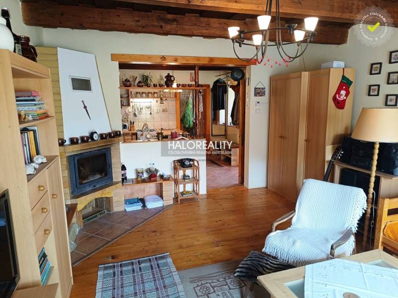 The interior of a cabin with a fireplace, wooden ceiling, cozy accessories, and comfortable furniture.