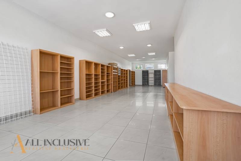 A space with light walls and wooden shelves has plenty of natural light.