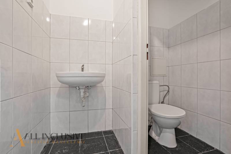 A restroom in commercial premises with white tiles and a sink.