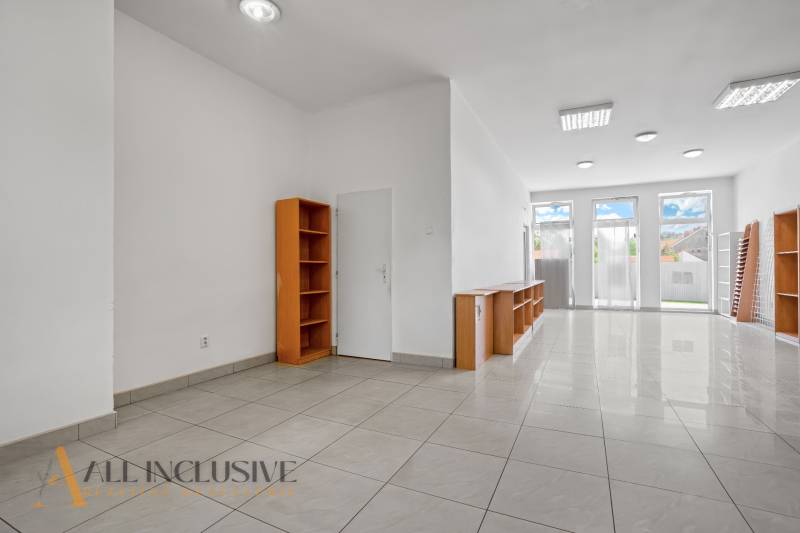 Commercial spaces with white walls and shelves, tiled floor, large windows.