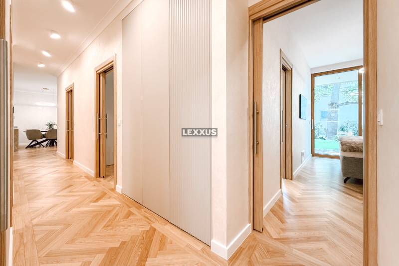 A hallway in a 4-room apartment with a wooden floor and a view into a room.