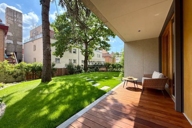 Terrace with a garden by a 4-room apartment, trees and buildings in the background.