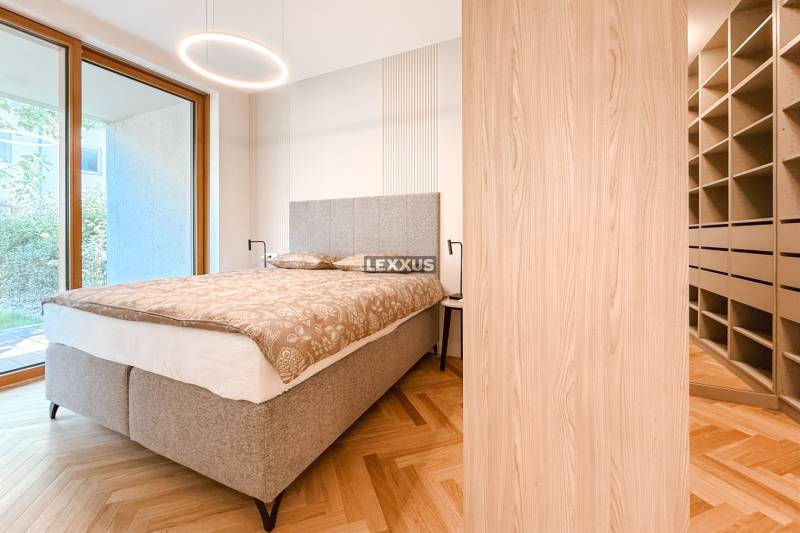 A bedroom with a gray bed, built-in wardrobe, parquet floors, and a view in a 4-room apartment.