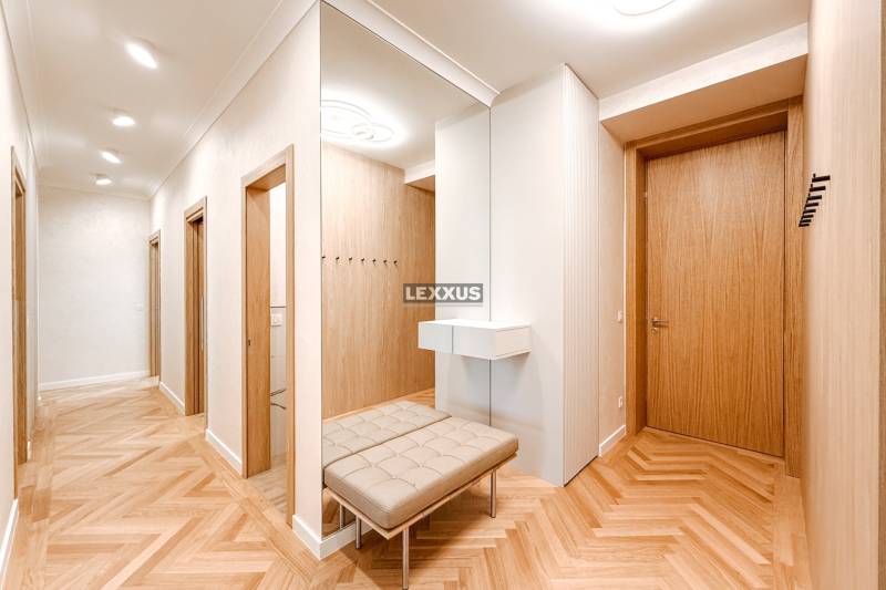 A spacious hallway with a mirror and a bench in a 4-room apartment with wooden doors.