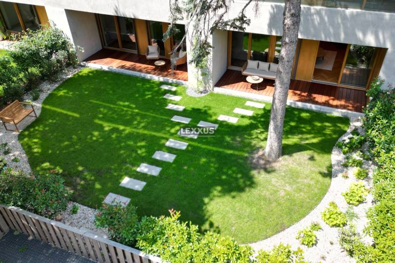 Garden terrace of a 4-room apartment with a lawn and wooden furniture.