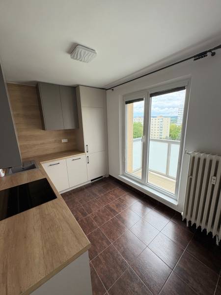 A kitchen in a 2-room apartment with a wooden countertop and access to a balcony.