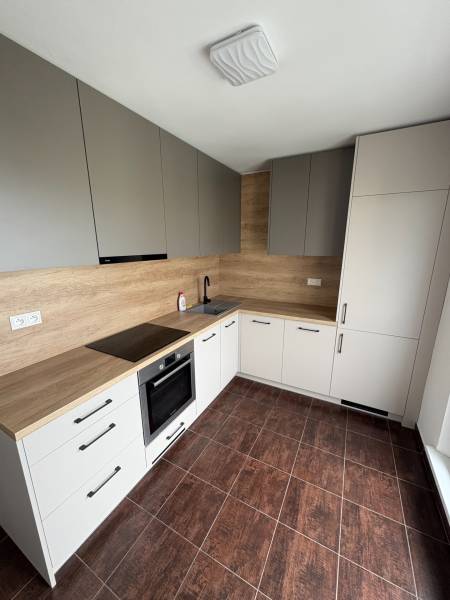 A kitchen in a 2-room apartment with wooden cabinets and dark tiles.
