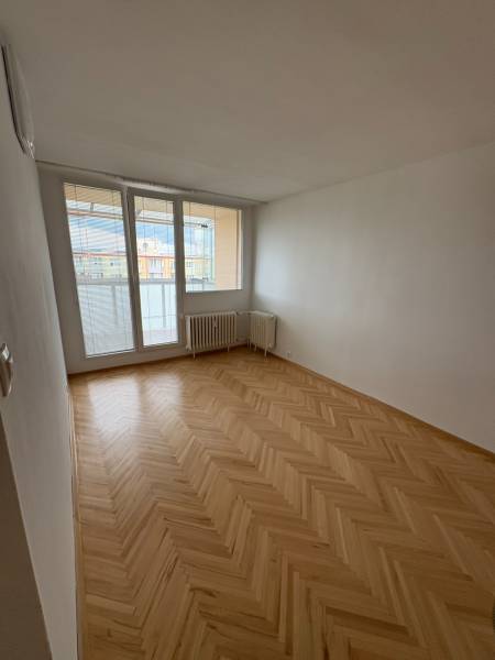 A room in a 2-room apartment with a parquet floor and a large window with a view.