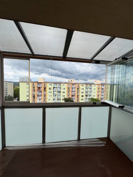 A glazed balcony with a view of colorful apartment buildings on SNP Street in Nová Dubnica.