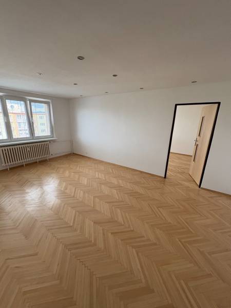 A room with a parquet floor, white walls, and windows, part of a 2-room apartment.