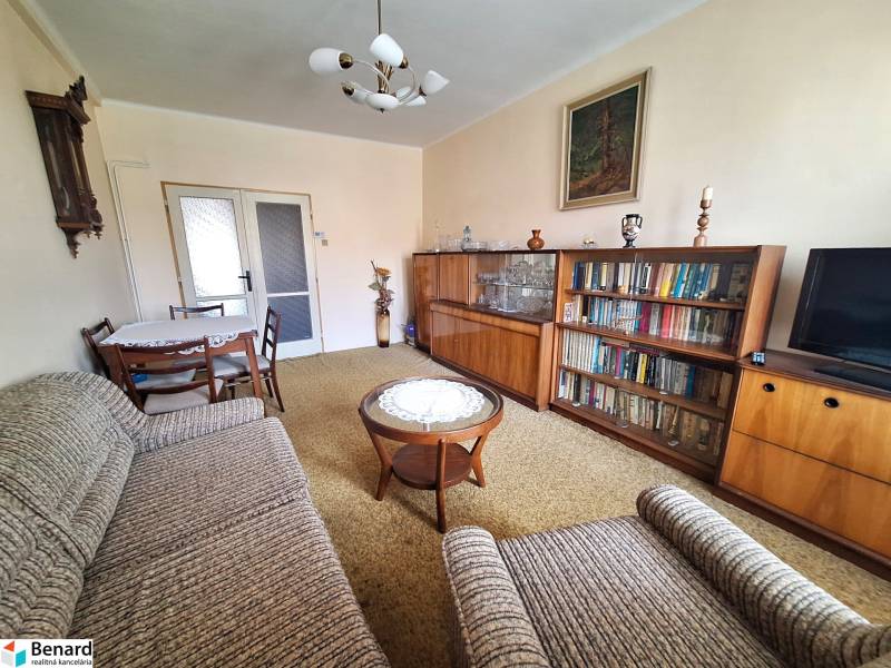 Living room in a 2-room apartment with a bookshelf, a sofa set, and a table with chairs.