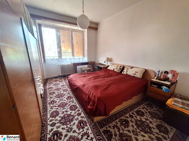 Bedroom in a 2-room apartment with a double bed, carpet, wardrobes, window with radiator.
