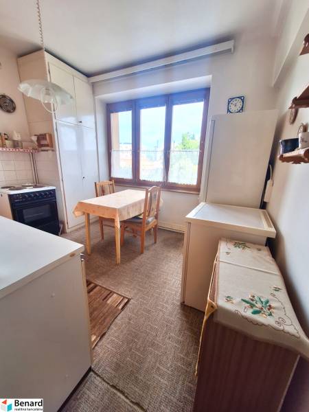 A kitchen in a 2-room apartment with a wooden dining table and a large window.