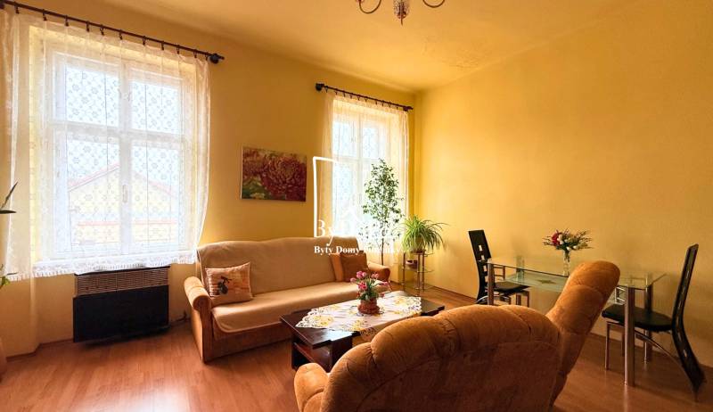 Living room in a family house with light furniture, flowers, and a dining table.
