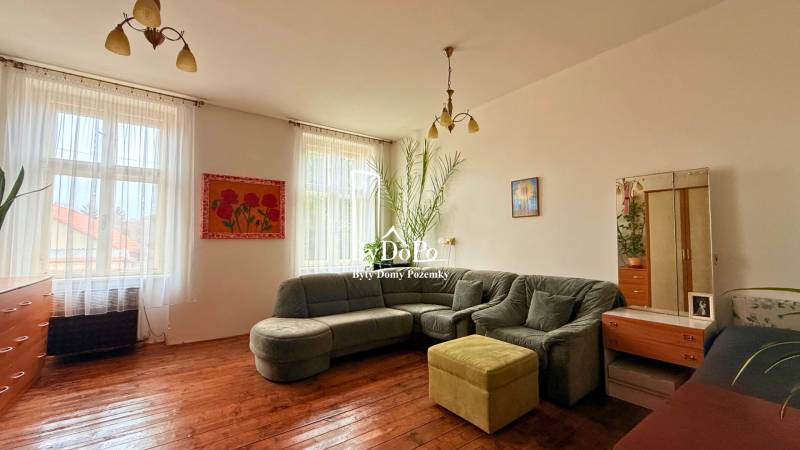 Living room in a family house with a corner sofa, wooden floor, and decorations.